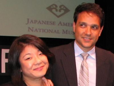 Aly Morita is wearing a black dress whereas Ralph Maccio is on a suit.